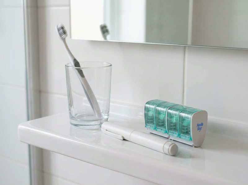 NeedleBay pen needle case beside a weekly injection pen on a bathroom shelf