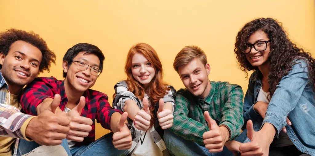 teenagers siting together with their thumbs up